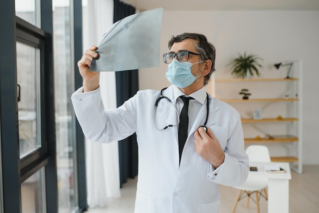 Доктор в маске и смотрит на рентген грудной клетки