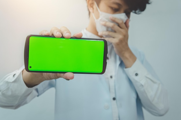 Doctor wearing medical Mask hand holding smartphone with green screen