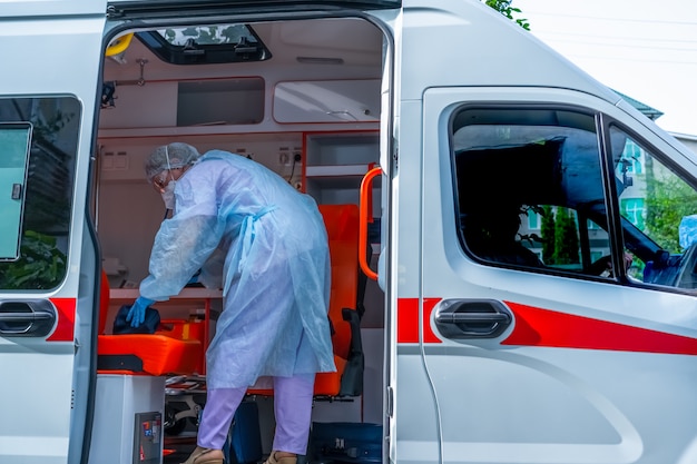 Фото Доктор, носящий защитную одежду от коронавируса в машине скорой помощи