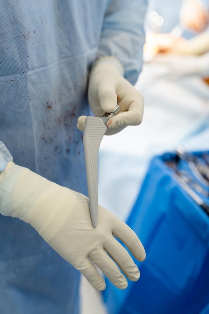 Doctor wearing scrubs holding special tool and showing it to the camera His clothes in blood Close up Medicine concept