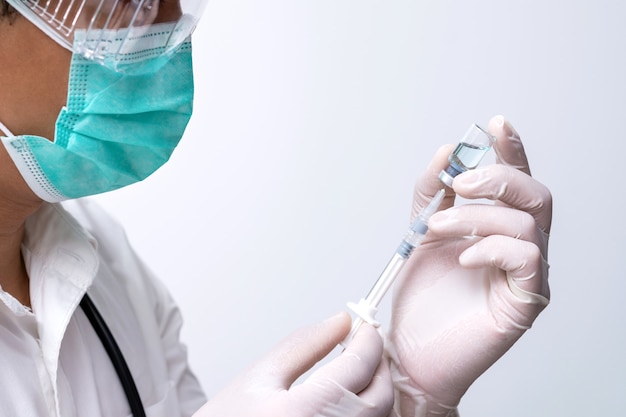 Doctor wears face mask and holding liquid vaccine vial bottle preparing for injection