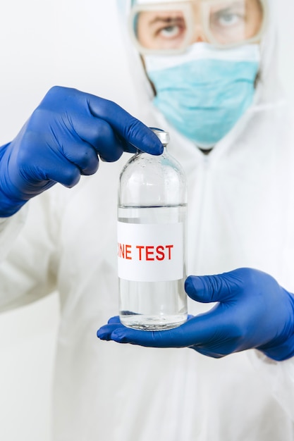 백색 외투와 파란 장갑에있는 의사는 코로나 바이러스 백신으로 주사기 테스트 튜브를 보유하고 있습니다. Covid 2019 백신 주사. 2020 유행성 코로나 바이러스. 백신 검사.