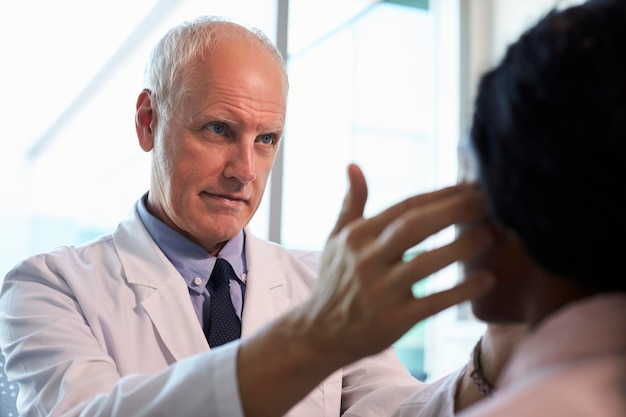 Photo doctor in white coat examining female patient in office