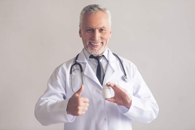 Doctor in white coat is holding a bottle of medicine.