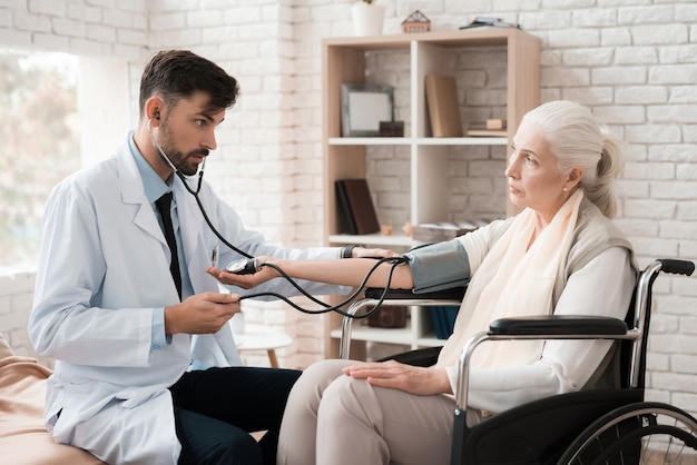 Doctor in a white coat measures the pressure of woman.