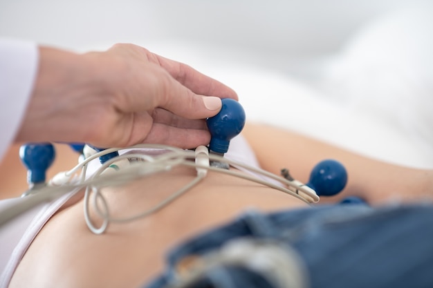 Doctor in white robe making electrocardiogram to the patient