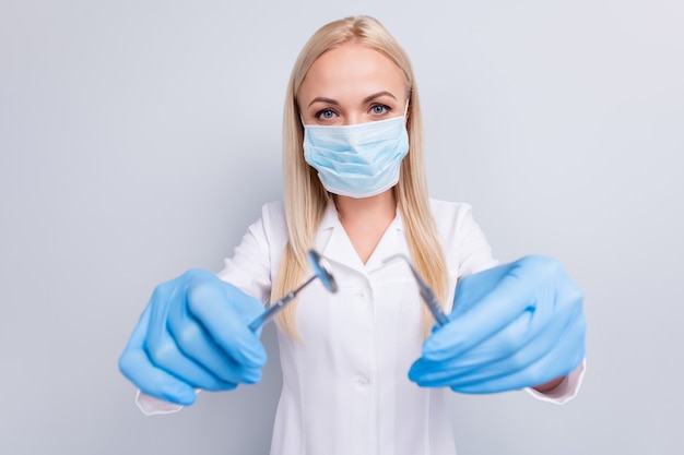 doctor in white suit holding dentist tools