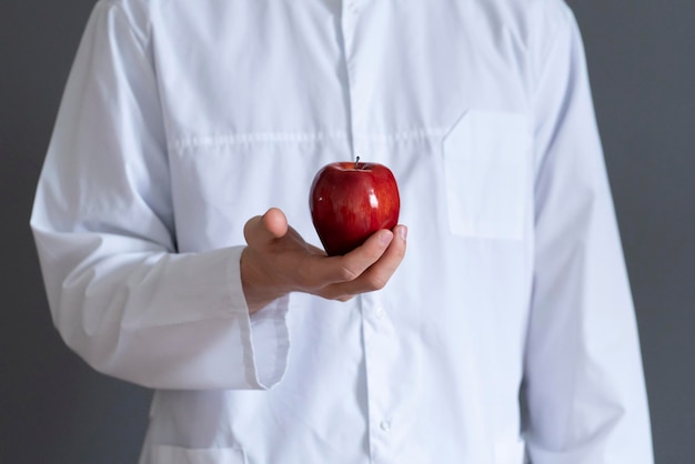健康食品のコンセプトを食べる患者に生の果物を与える白い制服を着た医師