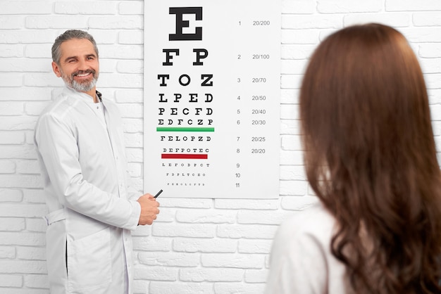 Doctor in white uniform standing near test eye chart.