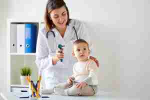 Photo doctor with baby and otoscope at clinic