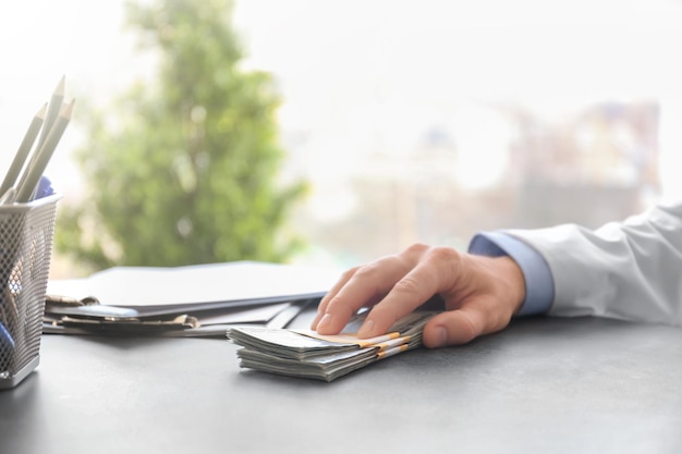 Doctor with bribe at workplace closeup