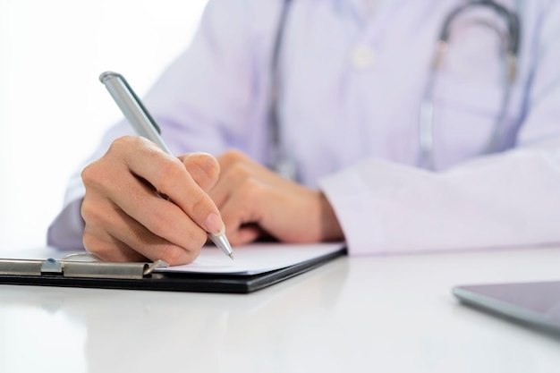 Doctor with a clipboard wrote on paper at the desk in the office