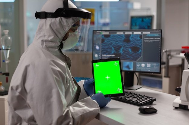 Фото Доктор в комбинезоне работает на планшете с зеленым экраном