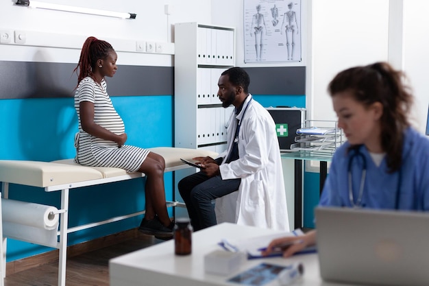 Doctor with digital tablet consulting pregnant patient