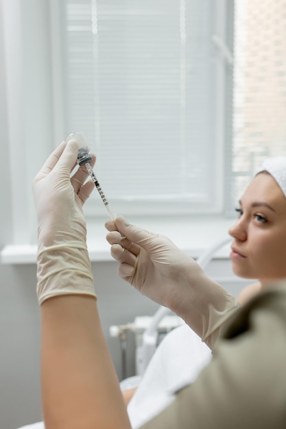 Un medico con i guanti sulle mani aspira un farmaco per la procedura in una siringa