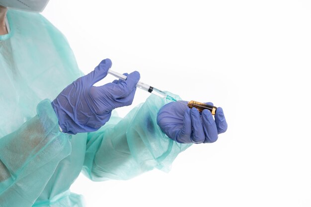 Doctor with gloves and mask preparing vaccine on white background