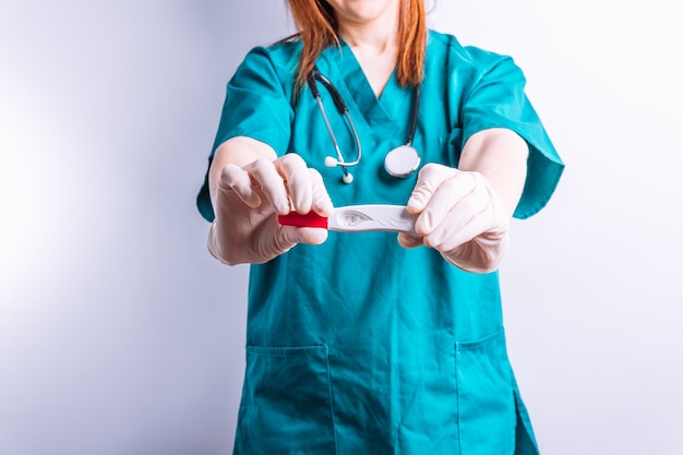 Doctor with gloves and stethoscope showing a pregnancy test to the positive to the front concept news of pregnancy