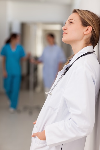 Doctor with her hands in her pockets against a wall