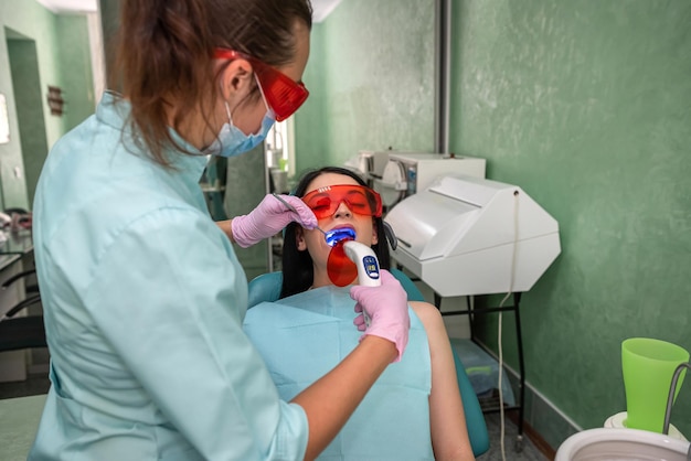 Doctor with lamp and mirror treating patients teeth close\
up