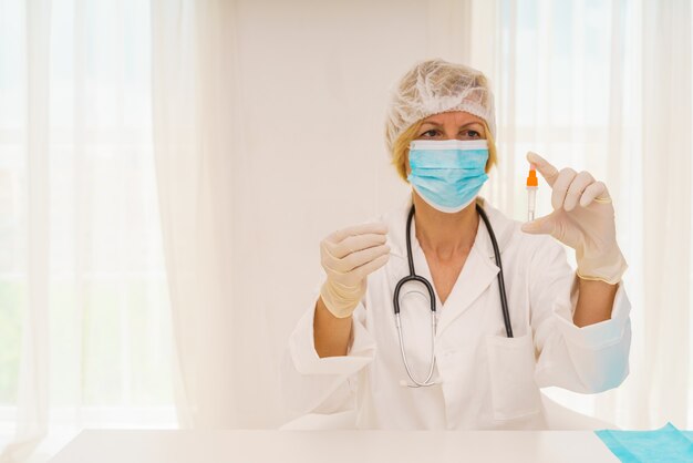 Photo doctor with mask and syringe is ready to administer the vaccine against covid