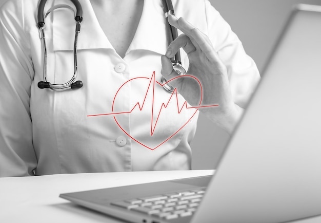 Doctor with ok gesture reporting electrocardiogram results to\
patient online using laptop remote medical consultation concept\
woman in lab coat sitting at table with computer black and\
white