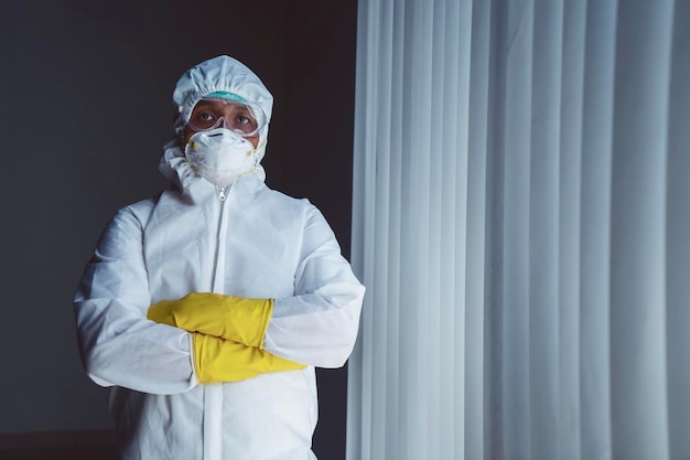 Doctor with protective suit standing by the window