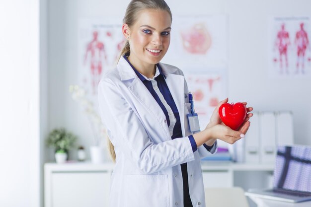 A doctor with stethoscope examining red heart isolated on white background