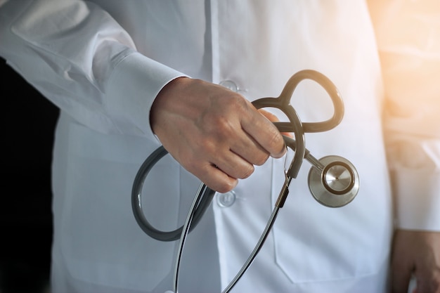 Doctor with stethoscope in hand on hospital background