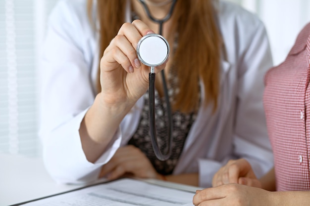 Doctor with a stethoscope in the hand. Physician  is ready to examine her female patient.