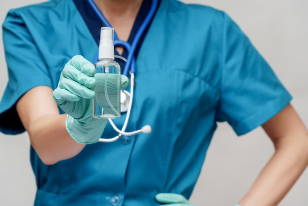 Doctor with stethoscope holding a bottle of sanitizer