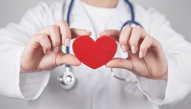 Doctor with stethoscope holding red heart.