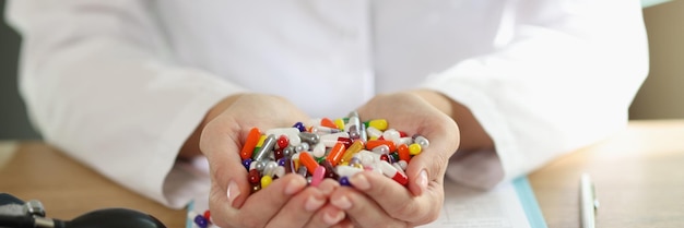 Doctor with stethoscope holds bunch of multicolored pills in her hands close up woman