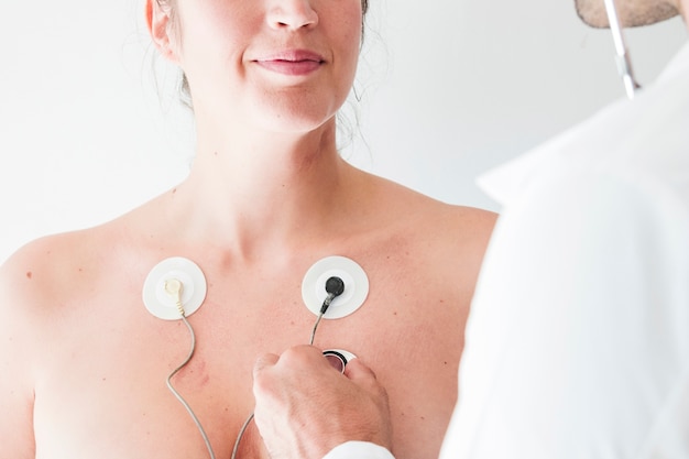 Photo doctor with stethoscope near female with electrodes