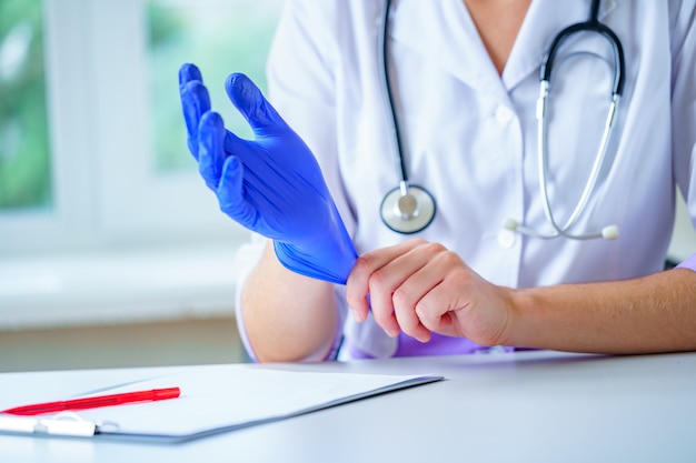 Medico con lo stetoscopio indossa guanti medici di gomma blu per visita medica di un paziente in un ospedale