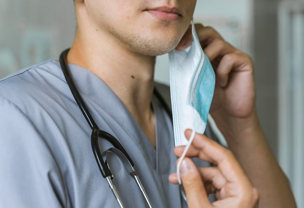 Photo doctor with stethoscope putting on medical mask