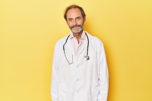 Doctor with stethoscope in yellow studio happy smiling and cheerful