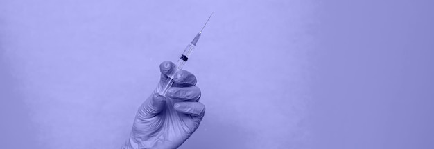 Photo doctor with a syringe in his hands. very peri, color of the year, 2022, blue, purple, selective focus.