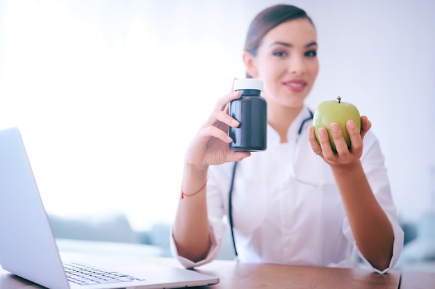 Doctor woman advising apple instead of pills. Healthy food