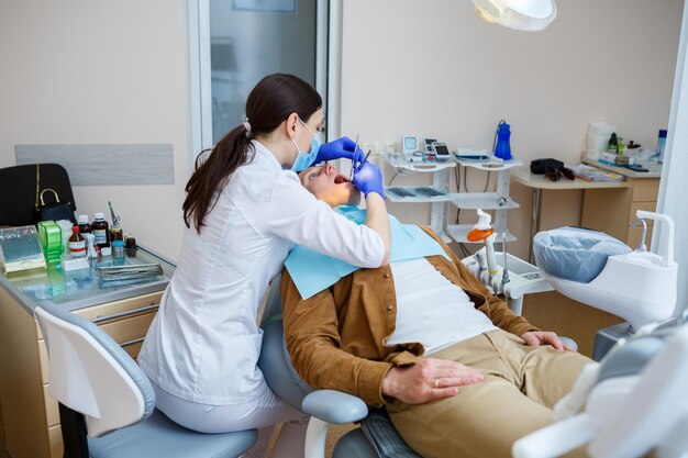医師の女性歯科医は、患者の歯を適切な歯科治療で治療します。歯科医療と衛生の概念。セレクティブフォーカス。