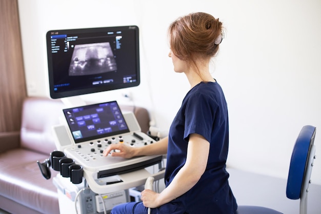 Doctor woman doing ultrasound scanning diagnostic of thyroid gland sitting in office in clinic