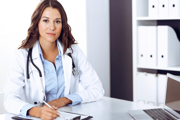 doctor woman filling up medical form while sitting at the desk in hospital office. physician at work. medicine and health care concept.
