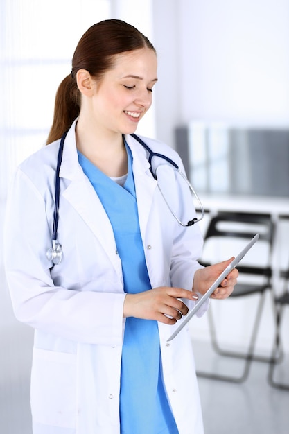 직장에서 의사 여자 또는 인턴 학생 서있는 동안 태블릿 컴퓨터를 사용하는 의사