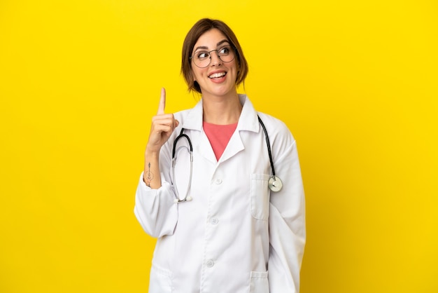 Doctor woman isolated on yellow background intending to realizes the solution while lifting a finger up