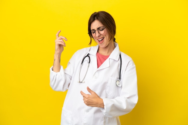 Doctor woman isolated on yellow background making guitar gesture