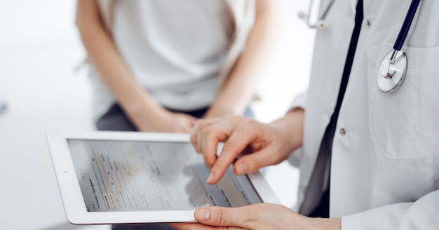 Foto medico donna e bambino paziente a casa. il pediatra che utilizza il tablet mentre compila le cartelle cliniche, da vicino. medicina, concetto sanitario.