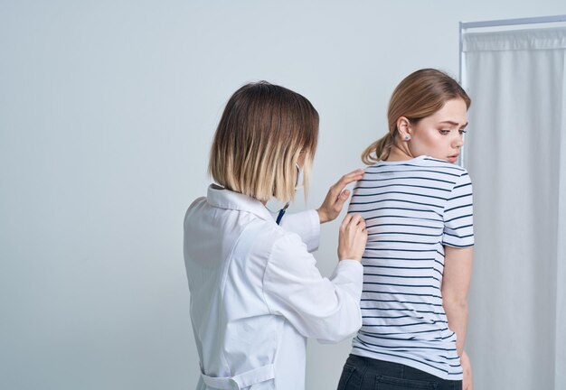 Doctor woman in medical gown with stethoscope listens to patient's heart high quality photo