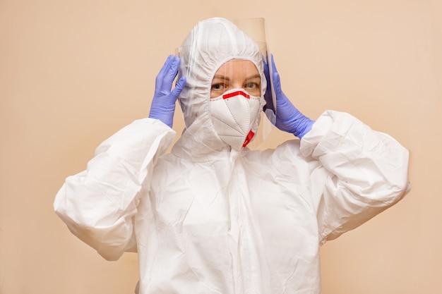 Foto medico donna in tuta protettiva per combattere il covid-19 (virus della corona). tuta protettiva, schermo protettivo, guanti, respiratore. concetto covid-19