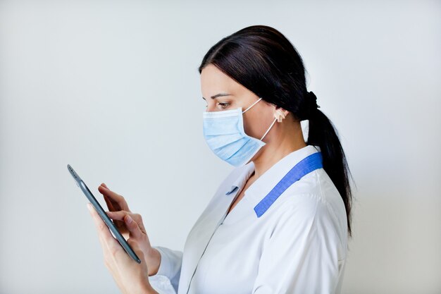 Doctor woman in uniform and mask with a tablet in her hands