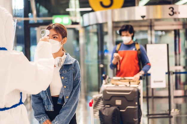 Doctor woman use infrared forehead thermometer for checking body temperature scan travel passenger fever in quarantine for coronavirus wearing safety protective mask at International terminal airport