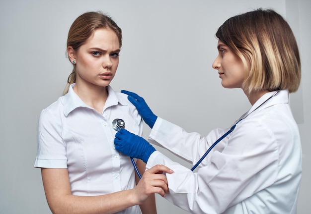 Doctor woman with a stethoscope holds a patient by the shoulder on a light background